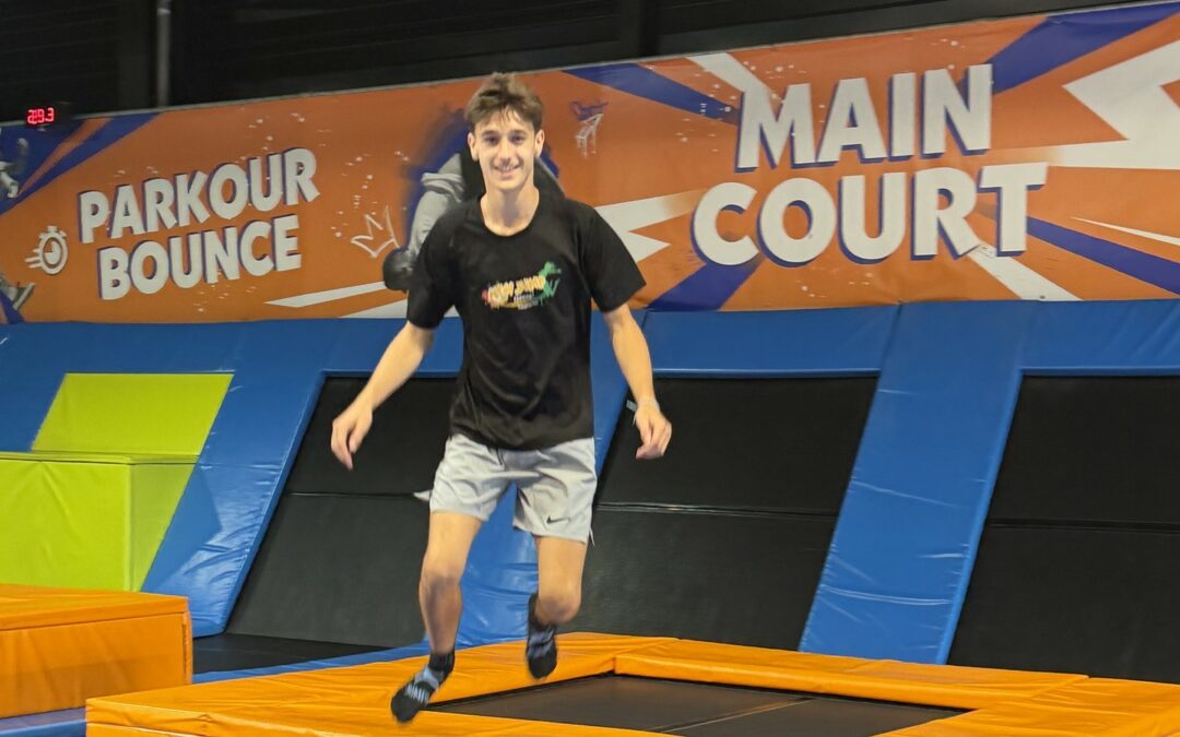 Un adolescent saute sur un trampoline du parc New Jump, devant les panneaux Parkour Bounce et Main Court